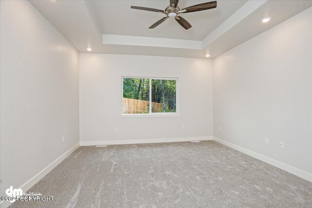 spare room featuring ceiling fan, a tray ceiling, and carpet flooring