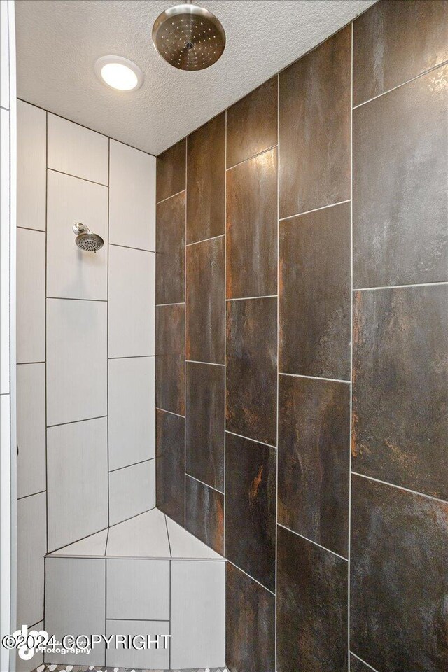 bathroom with tiled shower and a textured ceiling