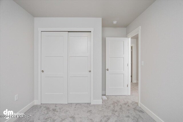 unfurnished bedroom with a closet and light colored carpet