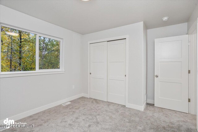 unfurnished bedroom featuring light carpet and a closet