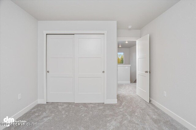 unfurnished bedroom with light carpet and a closet