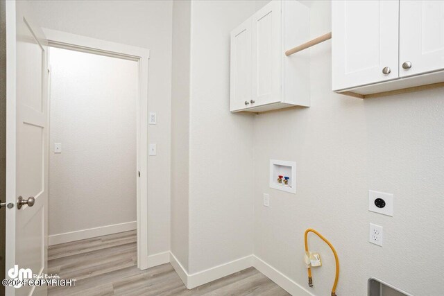 clothes washing area with light hardwood / wood-style floors, hookup for an electric dryer, hookup for a washing machine, and cabinets