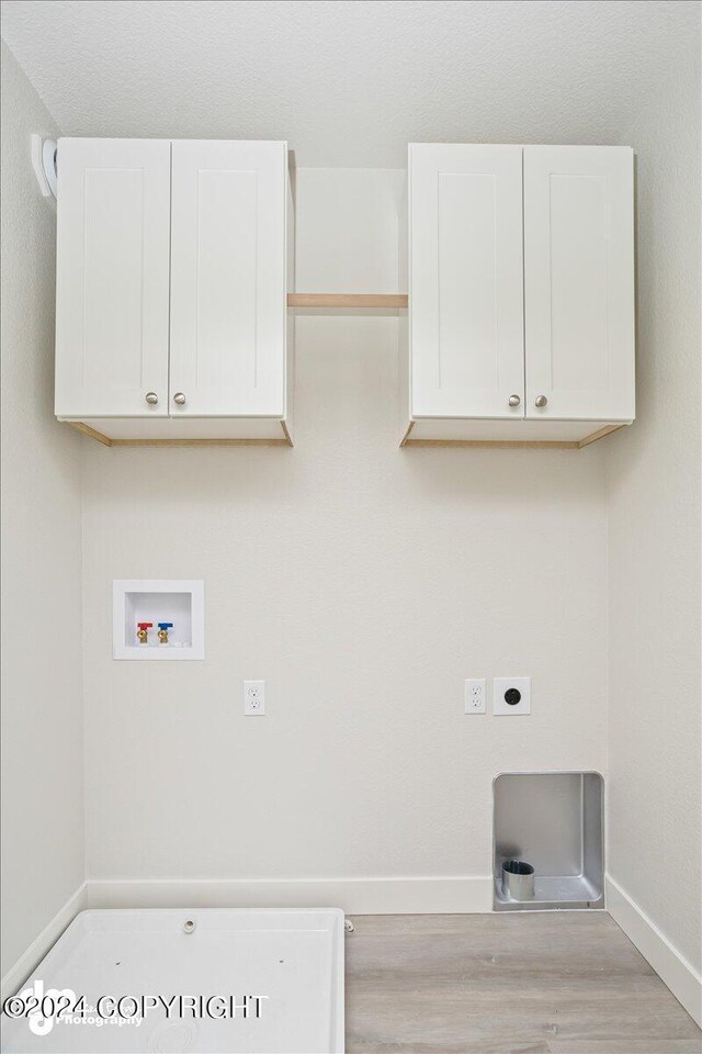 washroom featuring washer hookup, hookup for an electric dryer, light hardwood / wood-style floors, and cabinets