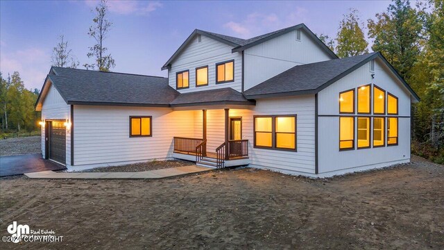 back house at dusk featuring a garage