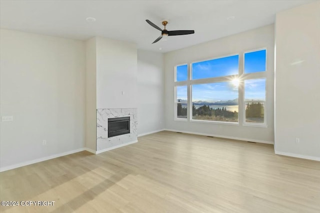 unfurnished living room featuring a fireplace, ceiling fan, and light hardwood / wood-style flooring