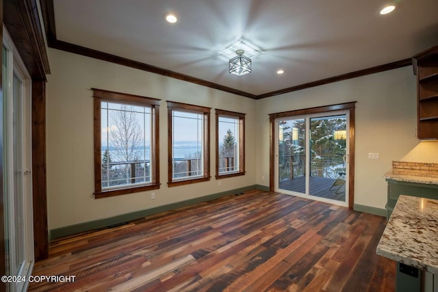 unfurnished dining area featuring a healthy amount of sunlight, crown molding, and dark wood-type flooring