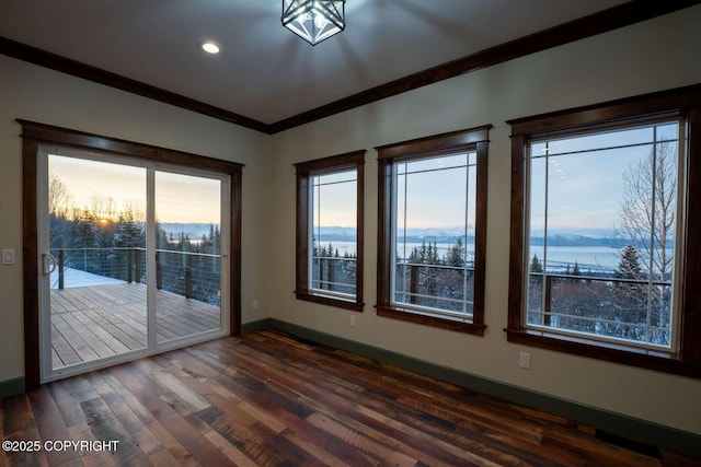 empty room with dark wood-type flooring, a water view, crown molding, and baseboards