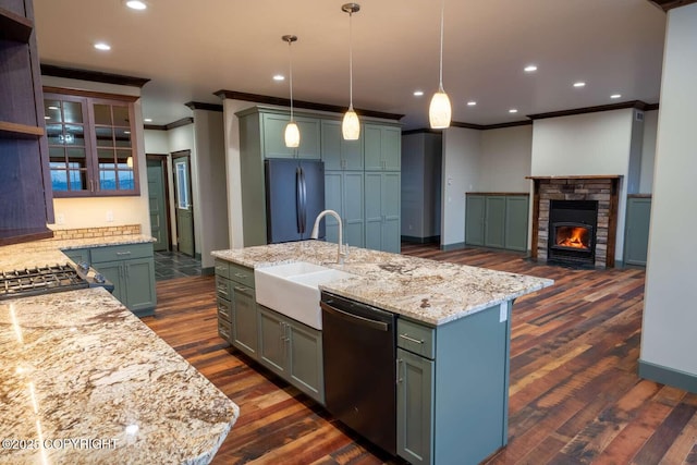 kitchen with glass insert cabinets, freestanding refrigerator, a sink, an island with sink, and dishwashing machine