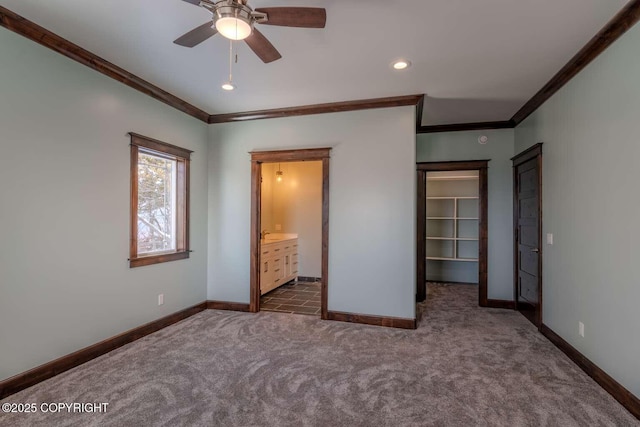 unfurnished bedroom featuring baseboards, a spacious closet, dark colored carpet, crown molding, and recessed lighting