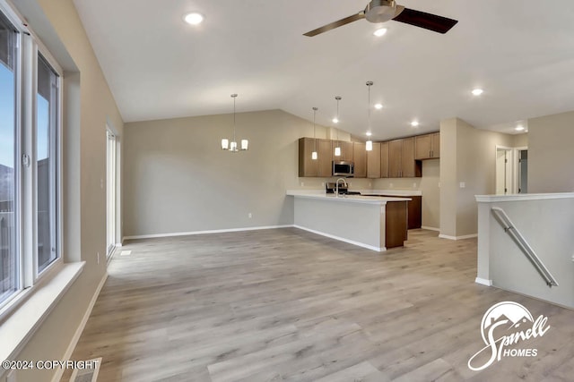 kitchen featuring lofted ceiling, light wood-type flooring, ceiling fan with notable chandelier, and decorative light fixtures