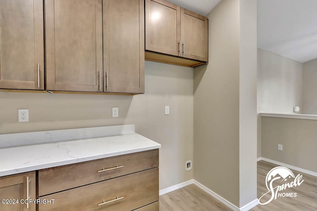 kitchen with light hardwood / wood-style flooring and light stone countertops