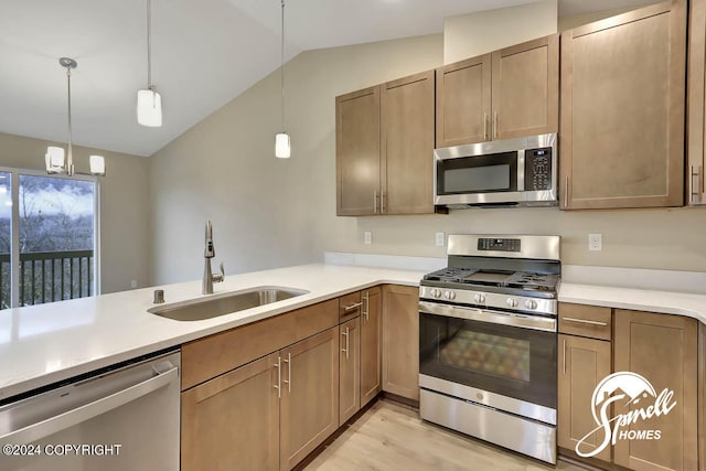 kitchen with decorative light fixtures, sink, stainless steel appliances, and vaulted ceiling