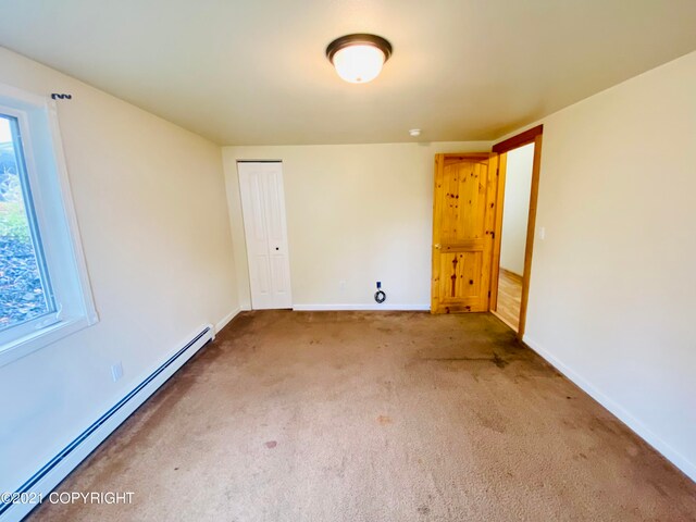 carpeted empty room featuring baseboard heating