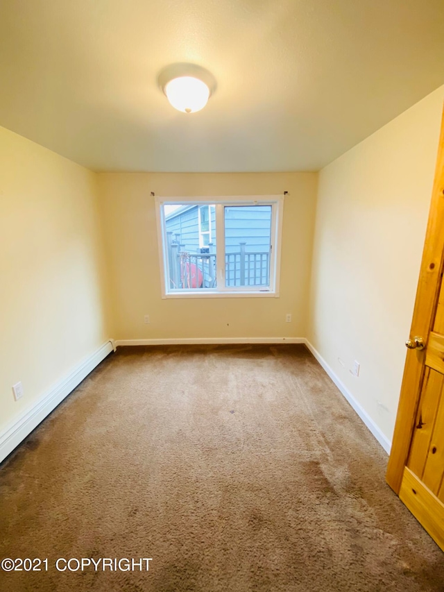 carpeted empty room with a baseboard heating unit