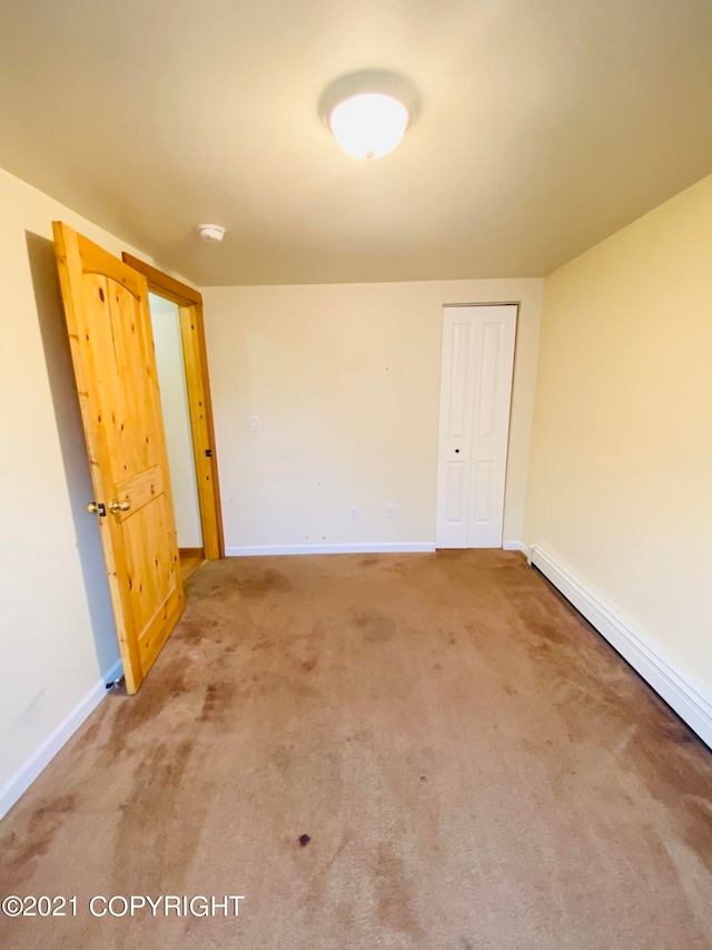 carpeted empty room featuring baseboard heating