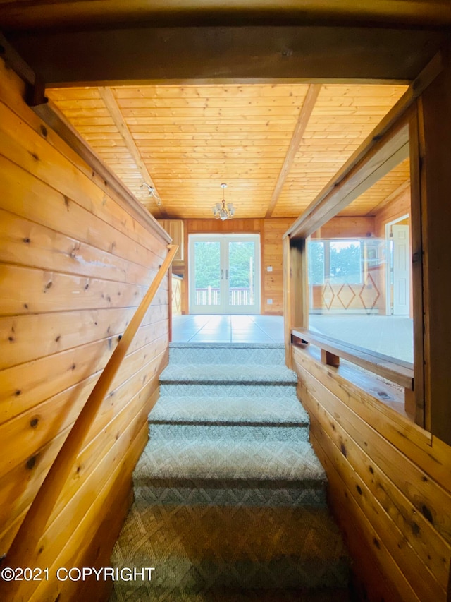 staircase featuring wooden ceiling, french doors, tile flooring, and wooden walls