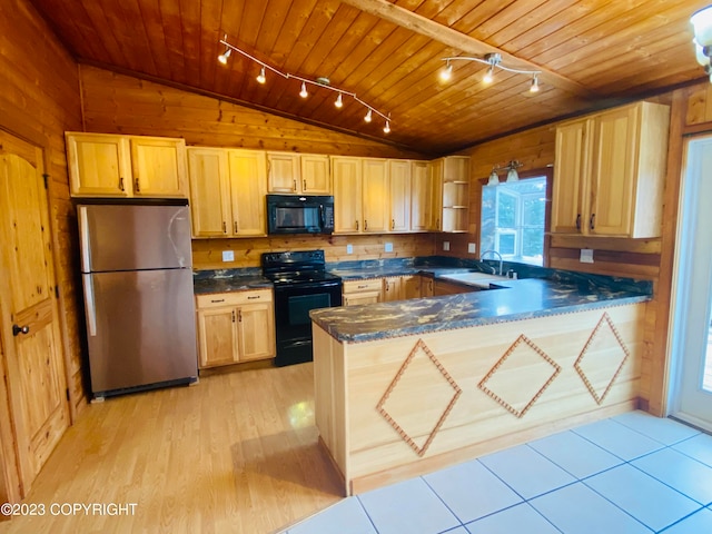 kitchen with black appliances, wood walls, vaulted ceiling, and rail lighting