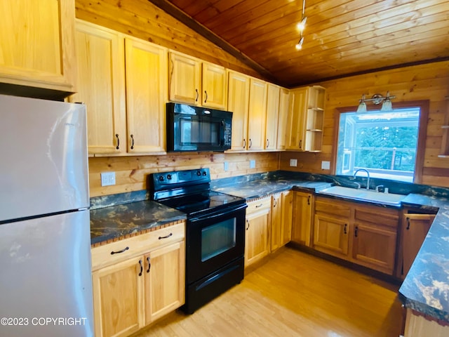 kitchen featuring vaulted ceiling, light hardwood / wood-style flooring, black appliances, sink, and wooden walls