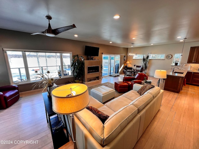 living room with a healthy amount of sunlight, ceiling fan, sink, and light wood-type flooring