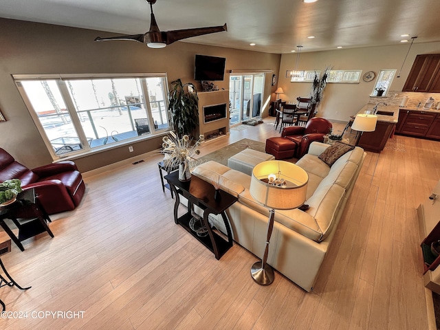 living room featuring light hardwood / wood-style floors, ceiling fan, and sink