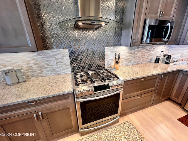 kitchen with backsplash, light hardwood / wood-style floors, stainless steel appliances, and light stone counters