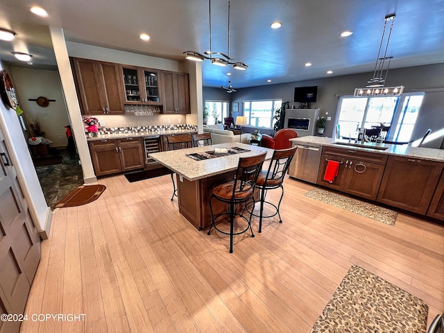 kitchen featuring light stone counters, a breakfast bar, sink, light hardwood / wood-style floors, and stainless steel dishwasher