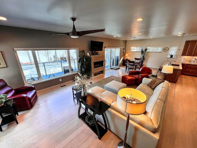 living room featuring a wealth of natural light, light hardwood / wood-style floors, ceiling fan, and sink