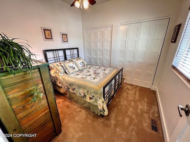 carpeted bedroom featuring ceiling fan and two closets