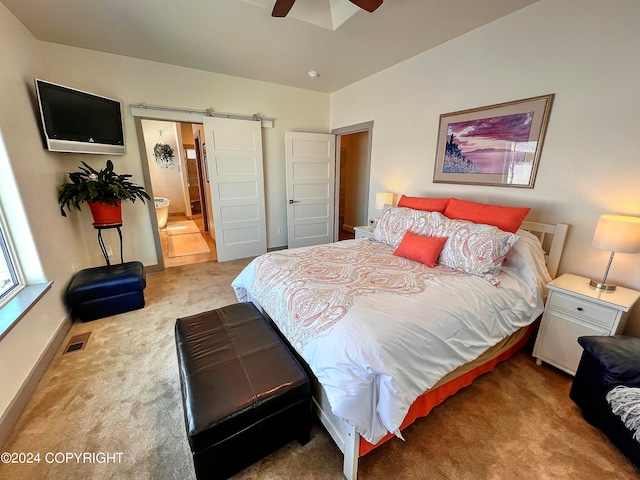 bedroom featuring light colored carpet, ceiling fan, and a barn door