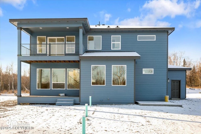 snow covered house featuring a balcony