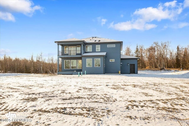 snow covered rear of property with a balcony