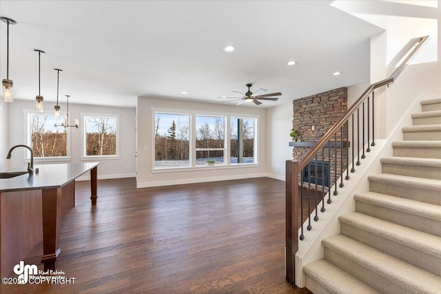 living room with dark hardwood / wood-style flooring, sink, and ceiling fan with notable chandelier