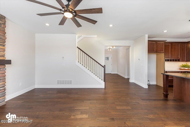 unfurnished living room featuring ceiling fan and dark hardwood / wood-style flooring