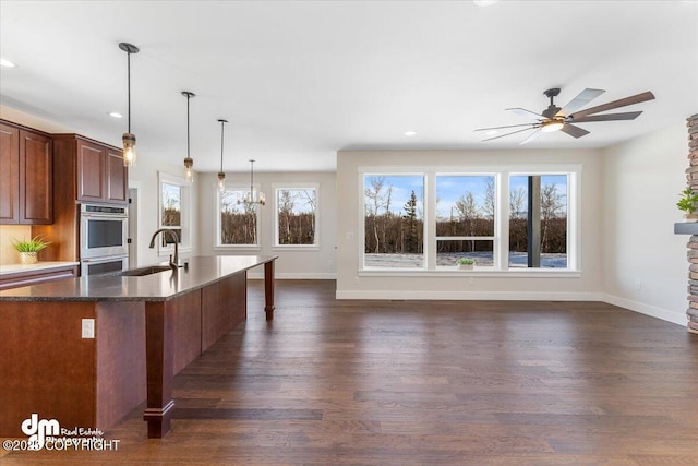 kitchen featuring pendant lighting, sink, dark stone countertops, double oven, and dark hardwood / wood-style flooring