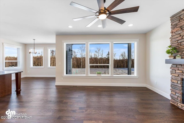 unfurnished living room featuring dark hardwood / wood-style flooring and ceiling fan with notable chandelier