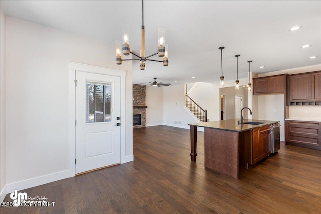 kitchen with dark hardwood / wood-style floors, decorative light fixtures, sink, a kitchen island with sink, and stainless steel dishwasher