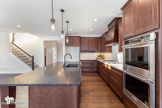 kitchen featuring stainless steel appliances, sink, pendant lighting, and a kitchen island with sink