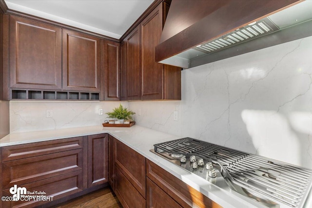 kitchen with tasteful backsplash, wall chimney range hood, and stainless steel gas cooktop