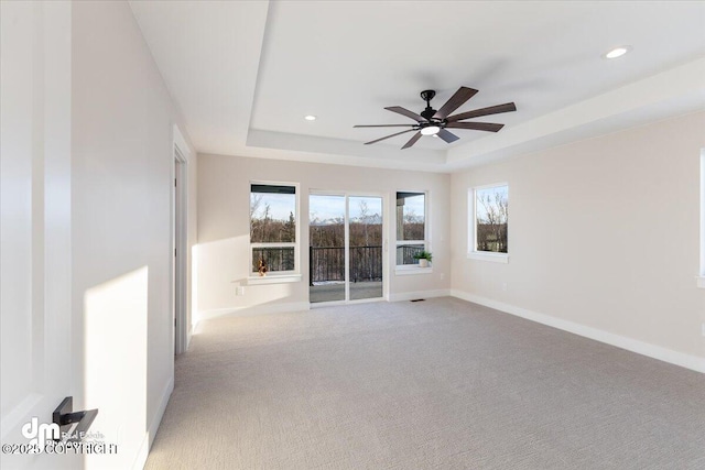 carpeted empty room featuring a raised ceiling and ceiling fan