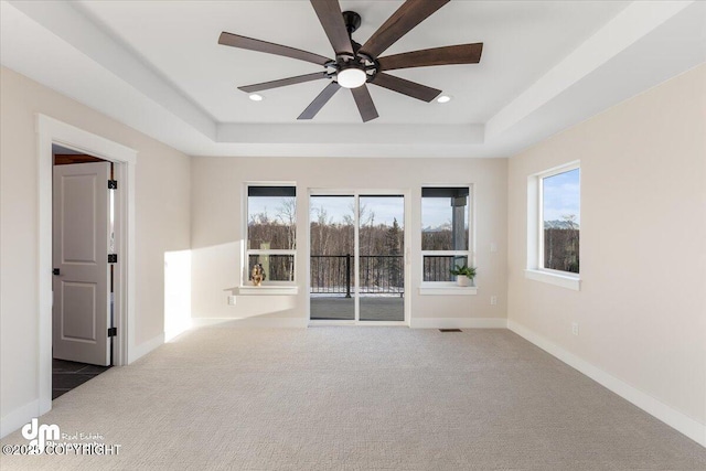 spare room with carpet floors, ceiling fan, and a tray ceiling