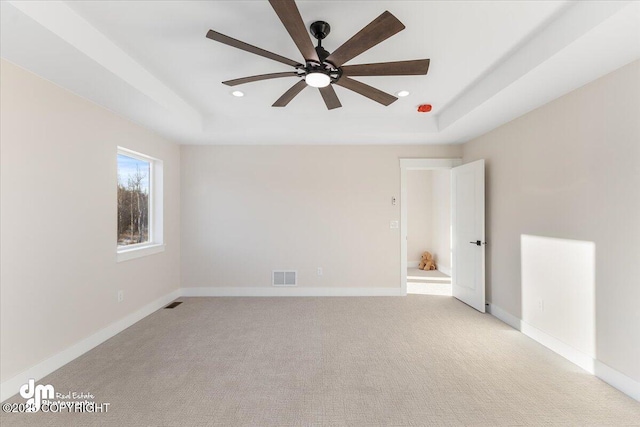 carpeted spare room featuring a raised ceiling and ceiling fan