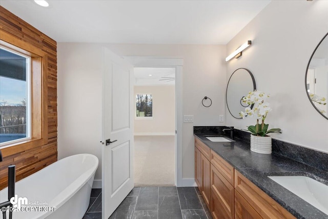 bathroom with vanity, a bathtub, and wood walls