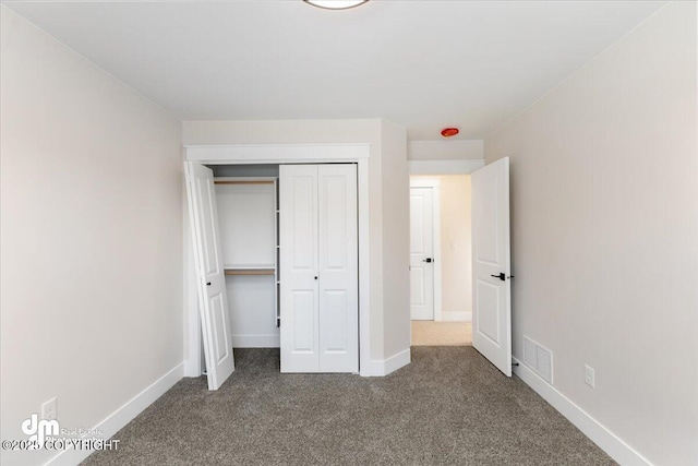 unfurnished bedroom with a closet and dark colored carpet