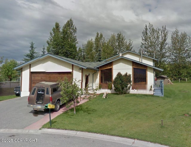 ranch-style home featuring a garage, driveway, and a front lawn