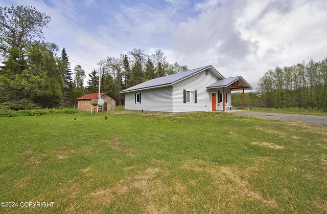 view of front of house with a porch, an outbuilding, and a front lawn