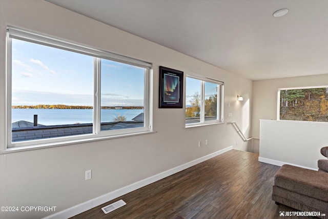 unfurnished room featuring dark hardwood / wood-style flooring and a water view