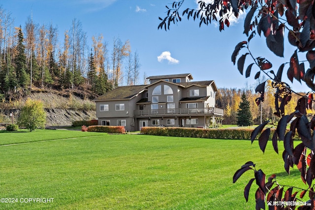 back of property with a balcony and a lawn