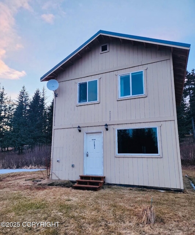 rear view of property featuring entry steps and a yard