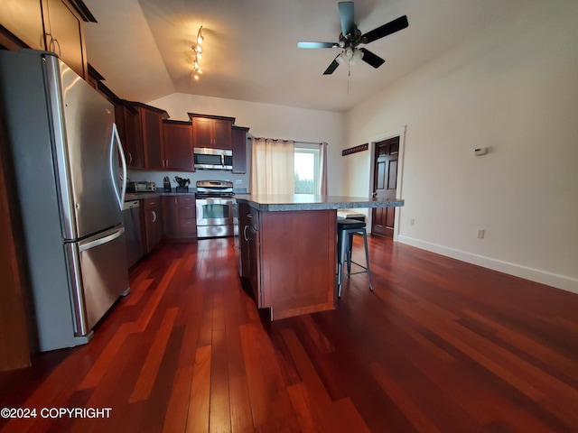 kitchen featuring a kitchen island, dark hardwood / wood-style flooring, a breakfast bar area, appliances with stainless steel finishes, and ceiling fan