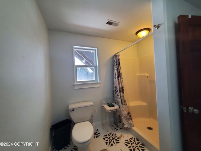 bathroom with a shower with shower curtain, tile patterned floors, and toilet